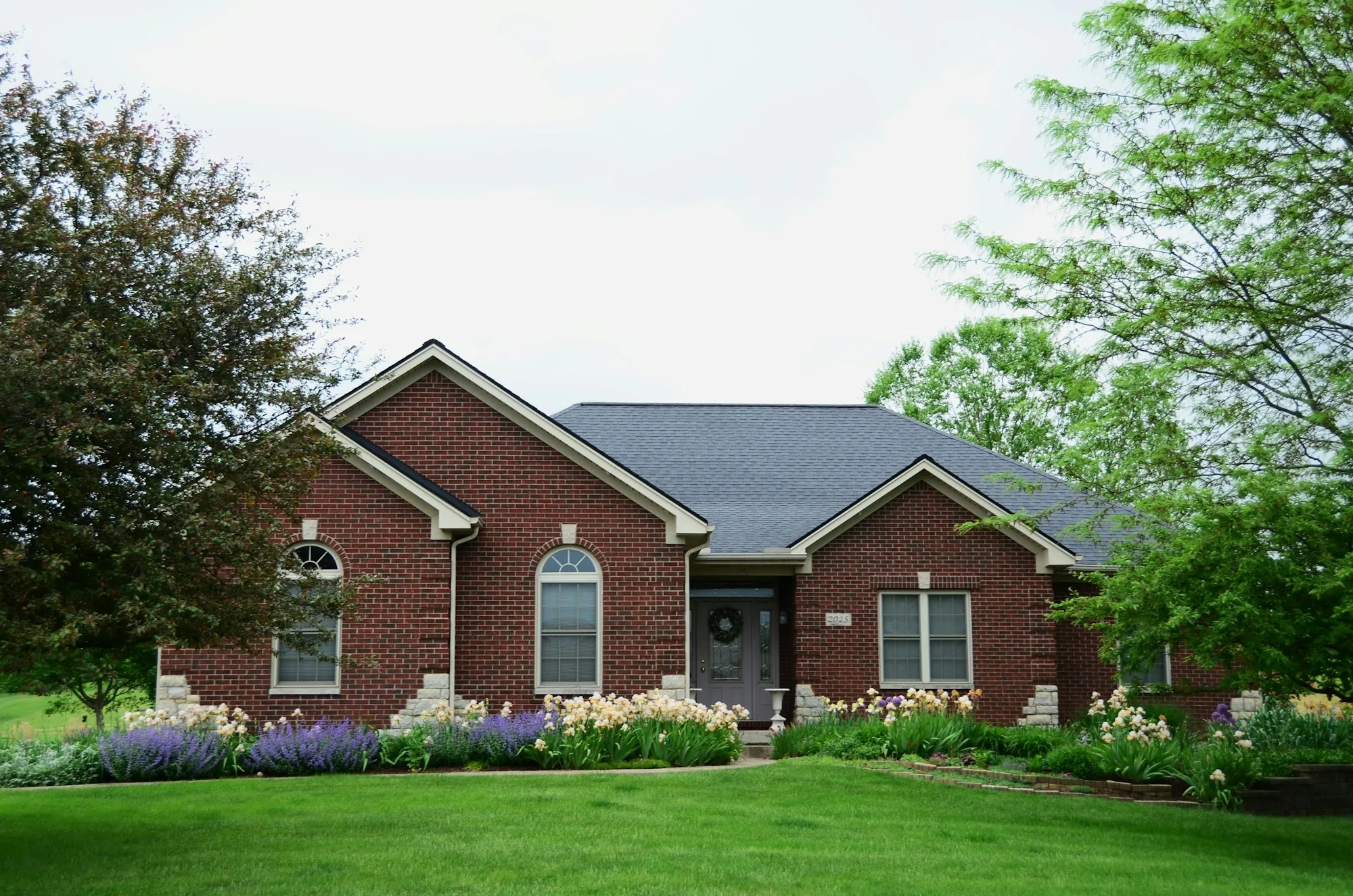 Brick ranch home with trees and a landscaped yard